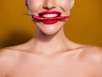 Mujer mordiendo un chile rojo Mujer mordiendo un chile rojo