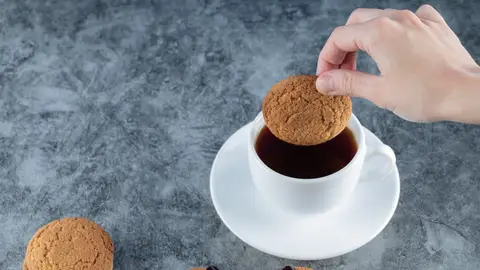 Persona mojando una galleta en café Persona mojando una galleta en café