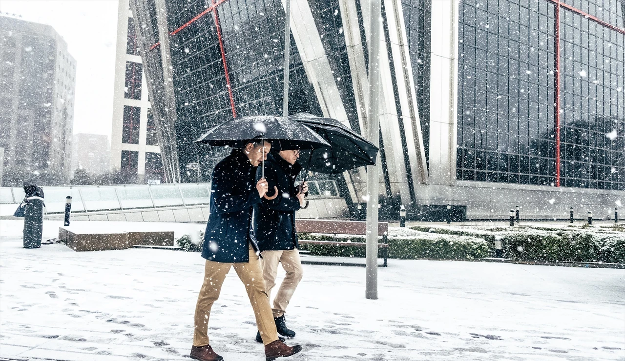Dos hombres caminando bajo la nieve en Madrid