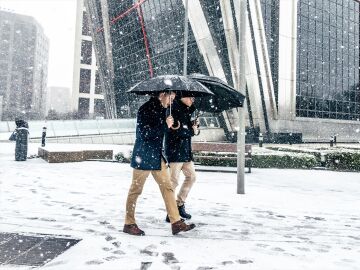 Dos hombres caminando bajo la nieve en Madrid