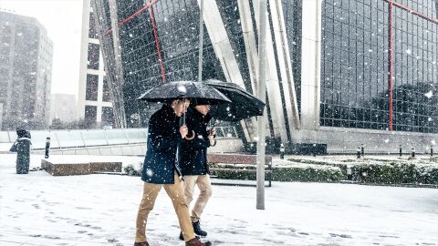 Dos hombres caminando bajo la nieve en Madrid