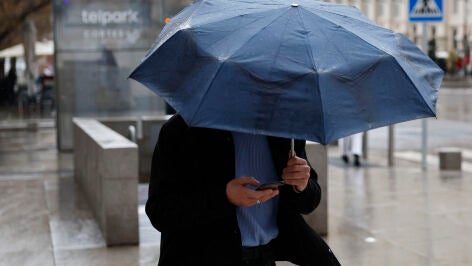 Imagen de un hombre protegi&eacute;ndose de la lluvia con un paraguas 