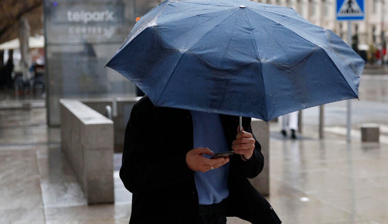 Imagen de un hombre protegi&eacute;ndose de la lluvia con un paraguas 