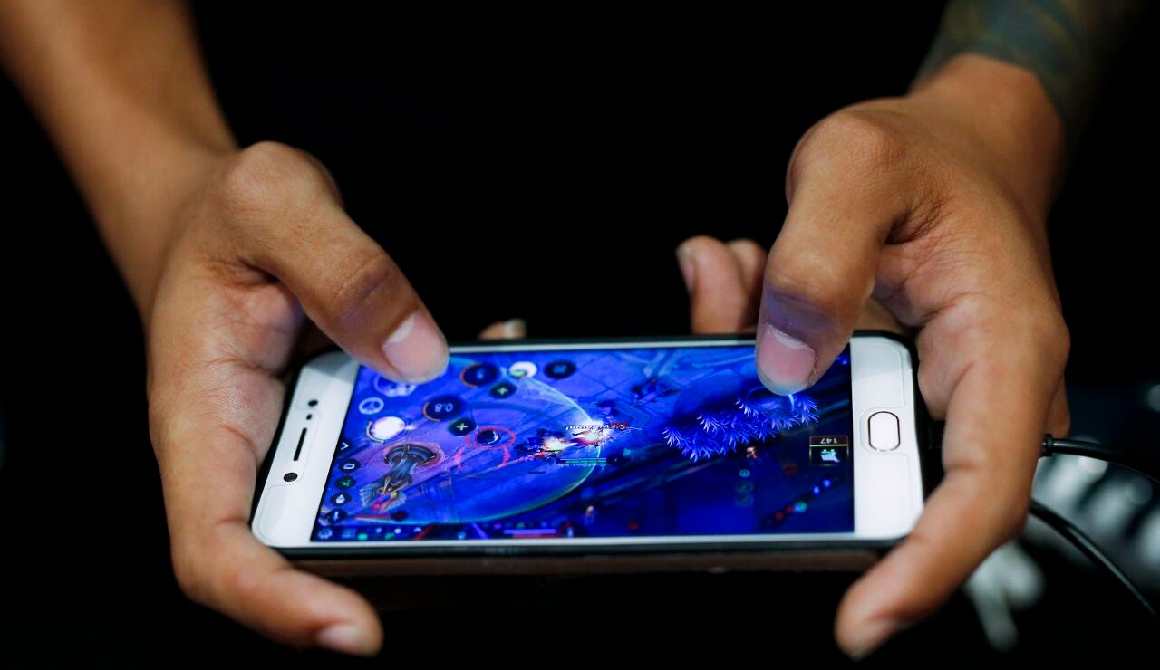 Imagen de archivo de un joven jugando online en un tel&eacute;fono m&oacute;vil