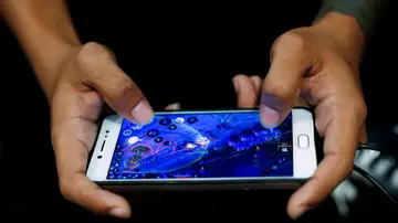 Imagen de archivo de un joven jugando online en un teléfono móvil Imagen de archivo de un joven jugando online en un teléfono móvil