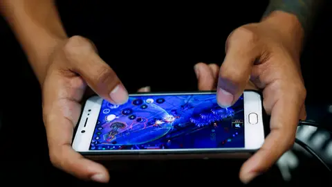 Imagen de archivo de un joven jugando online en un teléfono móvil Imagen de archivo de un joven jugando online en un teléfono móvil