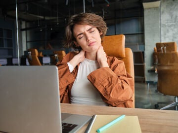 Mujer trabajando en la oficina con dolor de cervicales