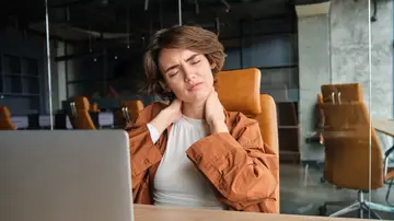 Mujer trabajando en la oficina con dolor de cervicales Mujer trabajando en la oficina con dolor de cervicales