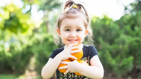 Niña sujetando tres naranjas Niña sujetando tres naranjas