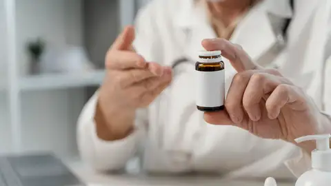 Médico con un bote de fármaco Médico con un bote de fármaco