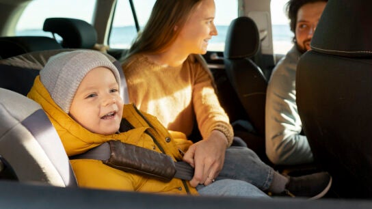 Ni&ntilde;o con abrigo en la sillita del coche
