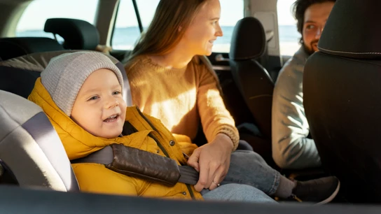 Niño con abrigo en la sillita del coche Niño con abrigo en la sillita del coche