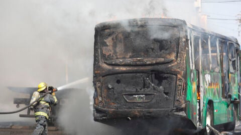 Un bombero apaga las llamas en un autob&uacute;s