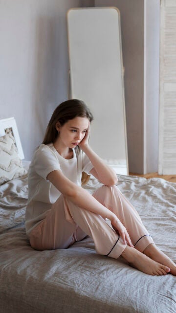 Mujer triste sentada en la cama