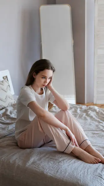 Mujer triste sentada en la cama Mujer triste sentada en la cama