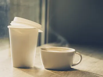 Dos cafés, uno en vaso de papel y el otro en taza de cerámica Dos cafés, uno en vaso de papel y el otro en taza de cerámica