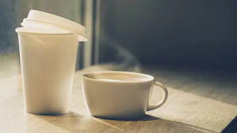 Dos cafés, uno en vaso de papel y el otro en taza de cerámica Dos cafés, uno en vaso de papel y el otro en taza de cerámica