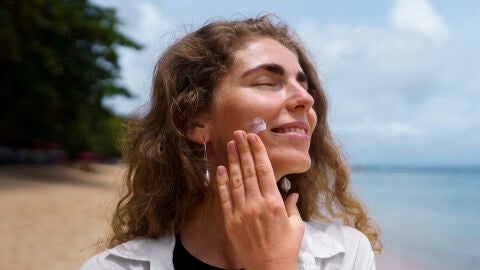 Mujer que se está poniendo crema solar facial