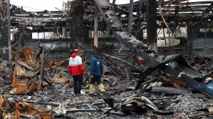 Miembros de la Media Luna Roja Iran&iacute; se encuentran entre los restos de veh&iacute;culos en un taller mec&aacute;nico en Teher&aacute;n