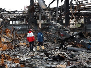 Miembros de la Media Luna Roja Iran&iacute; se encuentran entre los restos de veh&iacute;culos en un taller mec&aacute;nico en Teher&aacute;n