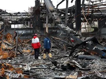 Miembros de la Media Luna Roja Iraní se encuentran entre los restos de vehículos en un taller mecánico en Teherán Miembros de la Media Luna Roja Iraní se encuentran entre los restos de vehículos en un taller mecánico en Teherán