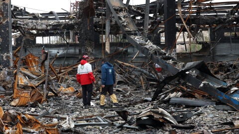 Miembros de la Media Luna Roja Iran&iacute; se encuentran entre los restos de veh&iacute;culos en un taller mec&aacute;nico en Teher&aacute;n