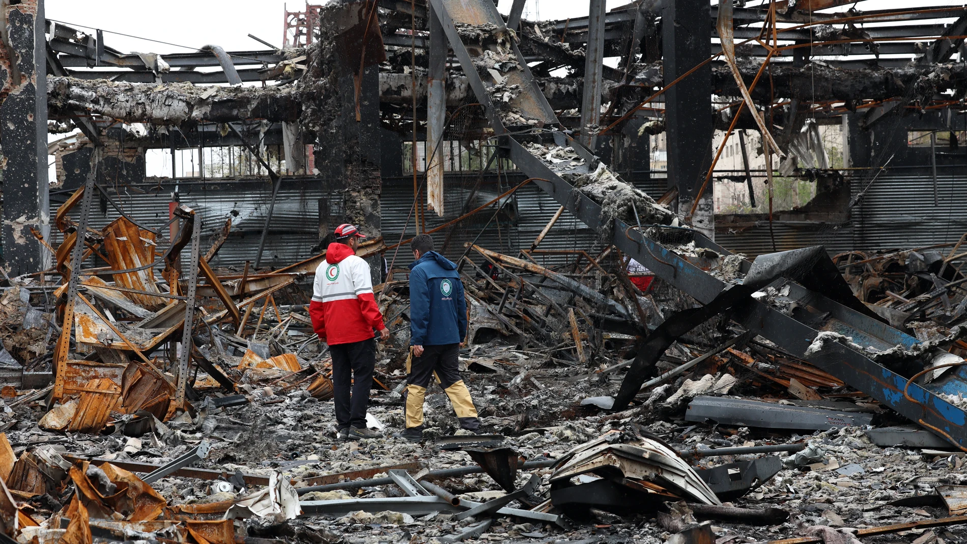 Miembros de la Media Luna Roja Iraní se encuentran entre los restos de vehículos en un taller mecánico en Teherán Miembros de la Media Luna Roja Iraní se encuentran entre los restos de vehículos en un taller mecánico en Teherán