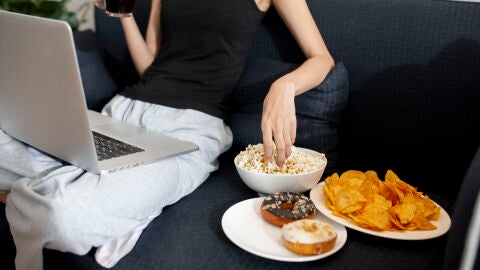 Mujer con palomitas, dónuts y patatas fritas