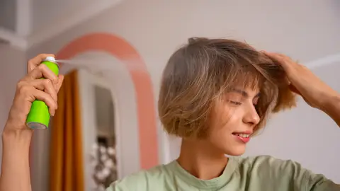 Mujer aplicándose champú en seco Mujer aplicándose champú en seco