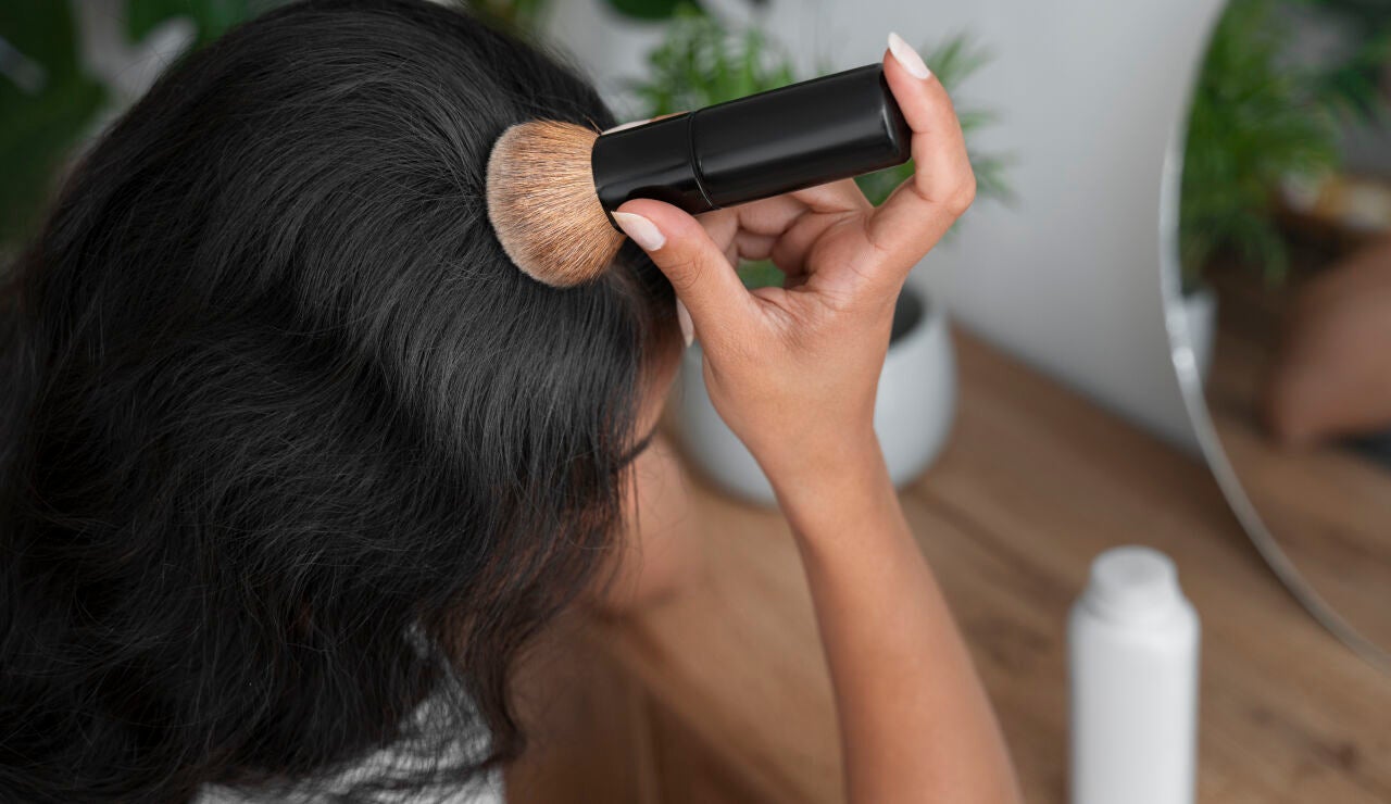 Mujer aplic&aacute;ndose champ&uacute; seco en polvo