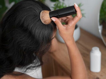 Mujer aplic&aacute;ndose champ&uacute; seco en polvo