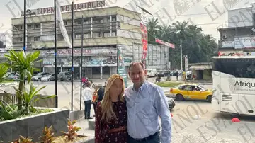 José Luis Ábalos y Andrea de la Torre, posan frente a la bandera de Camerún en una calle de Douala José Luis Ábalos y Andrea de la Torre, posan frente a la bandera de Camerún en una calle de Douala