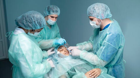 Paciente y médicos en una operacióin de rinoplastia 