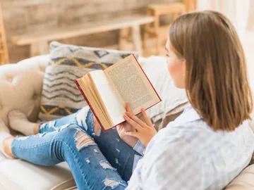 Mujer leyendo un libro en el sofá Mujer leyendo un libro en el sofá