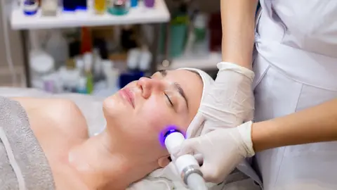 Mujer haciéndose un tratamiento facial con láser Mujer haciéndose un tratamiento facial con láser