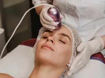 Mujer haciéndose un tratamiento facial con láser Mujer haciéndose un tratamiento facial con láser
