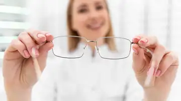 Óptica con unas gafas en la mano Óptica con unas gafas en la mano