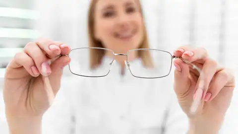 Óptica con unas gafas en la mano Óptica con unas gafas en la mano