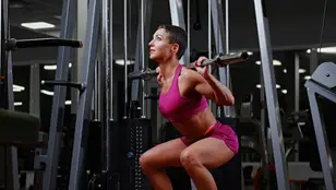 Mujer haciendo sentadillas en el gimnasio