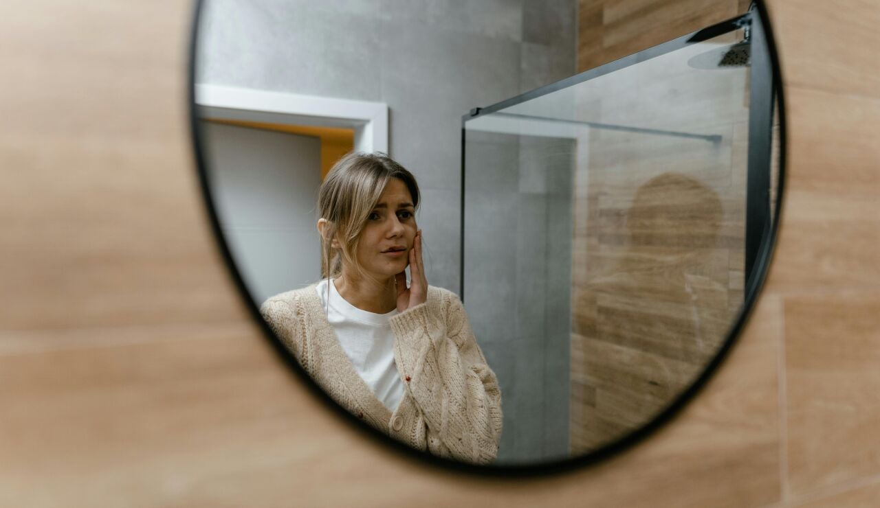 Mujer mir&aacute;ndose en el espejo pensativa