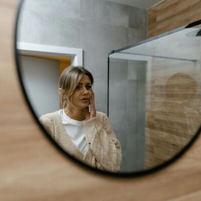 Mujer mir&aacute;ndose en el espejo pensativa