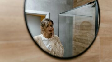 Mujer mir&aacute;ndose en el espejo pensativa
