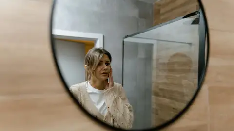 Mujer mirándose en el espejo pensativa Mujer mirándose en el espejo pensativa