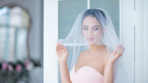 Novia con un vestido rosa con velo blanco