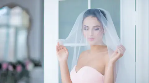 Novia con un vestido rosa con velo blanco Novia con un vestido rosa con velo blanco