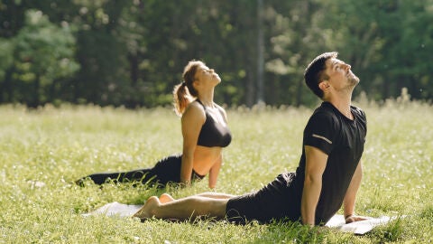 Pareja haciendo yoga en el parque