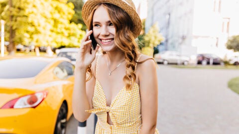 Mujer con un vestido amarillo hablando por el móvil en la calle
