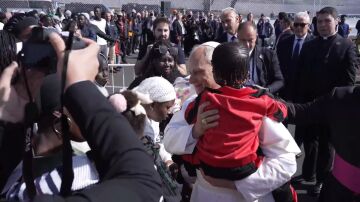 El Papa coge a un niño en brazos en 'Las Raíces'.