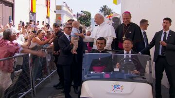 El papa bendice a un niño desde el papa móvil.