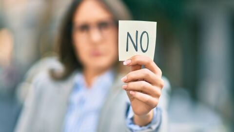 Mujer sujeta un papel con un "no" escrito